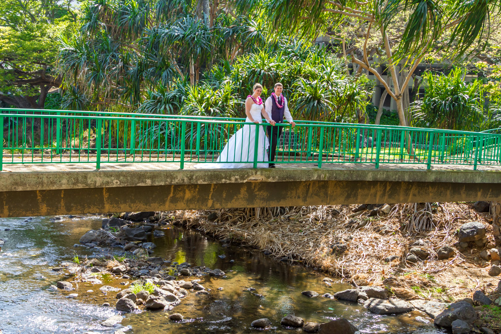 Couple standing on the bridge with greenery and rocks below