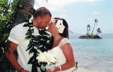 Bride in white florals and groom in maile lei